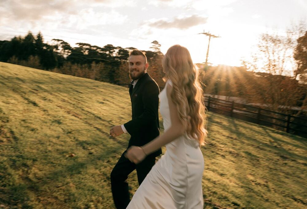Couple walking across a hillside at sunset