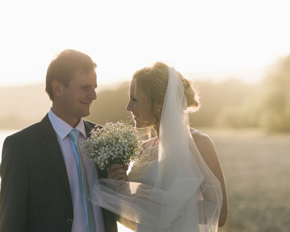 Groom and bride with a bouquet and veil at sunset
